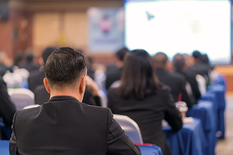 Mehrere Personen sitzen in einem Raum und gucken sich eine Präsentation an