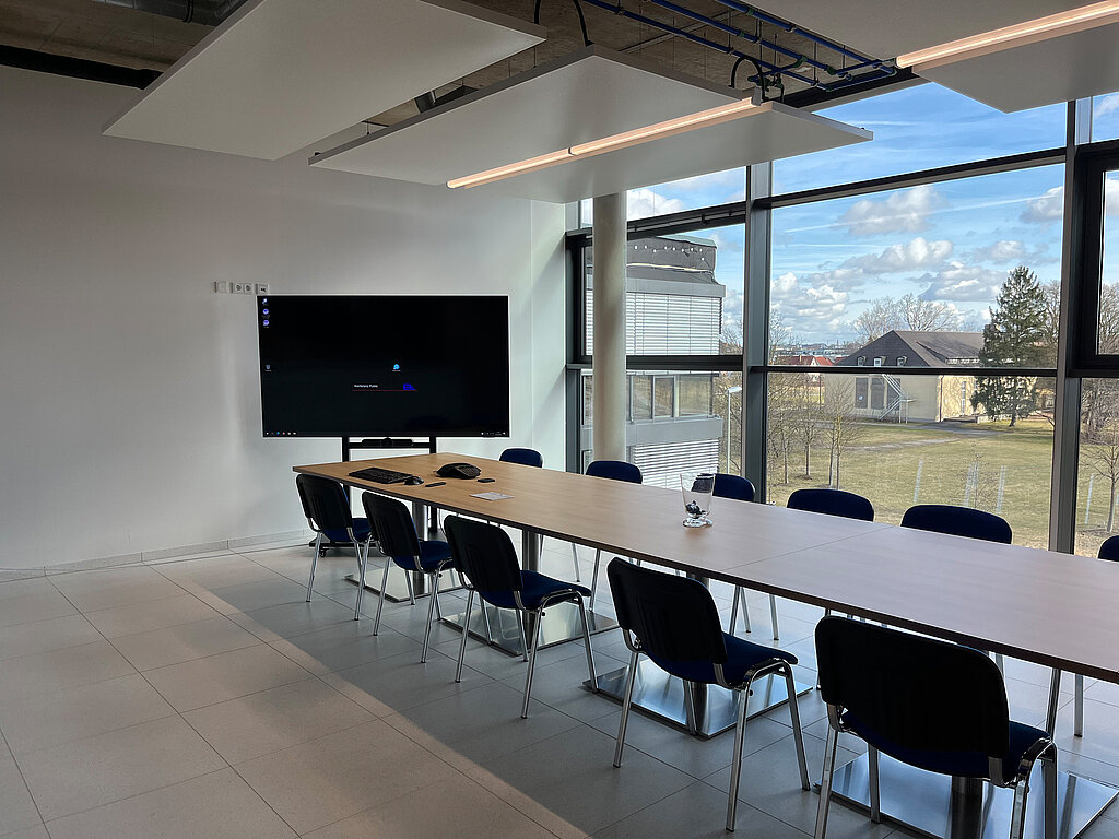 Conference room from E+L with screen, long table and several chairs