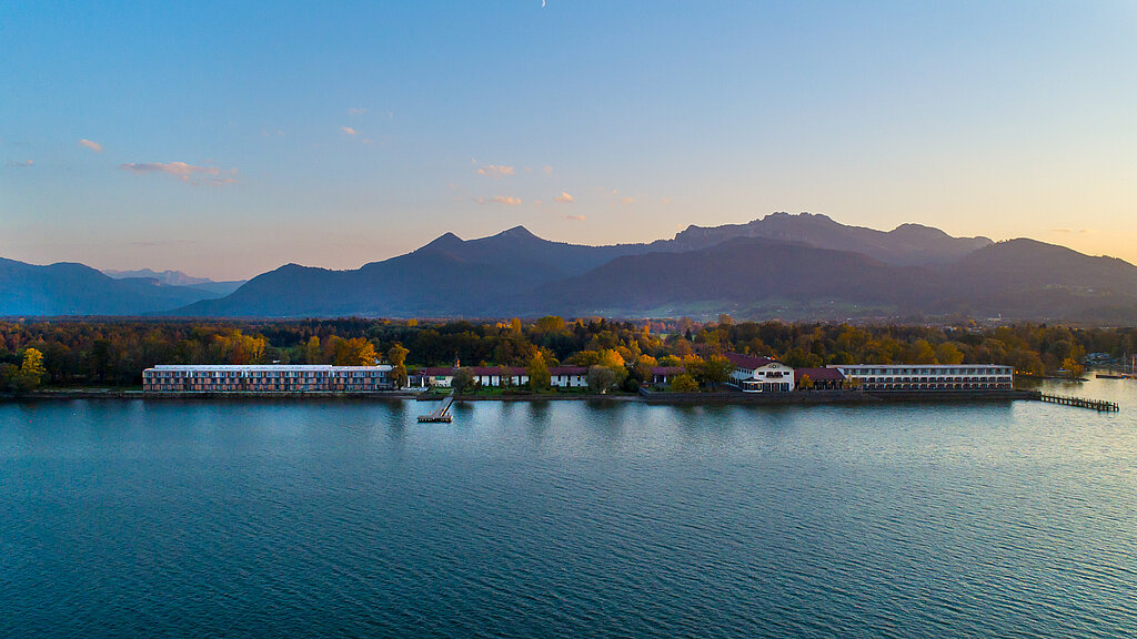Medical Park am Ufer, im Hintergrund Bäume und Berge, im Vordergrund der Chiemsee