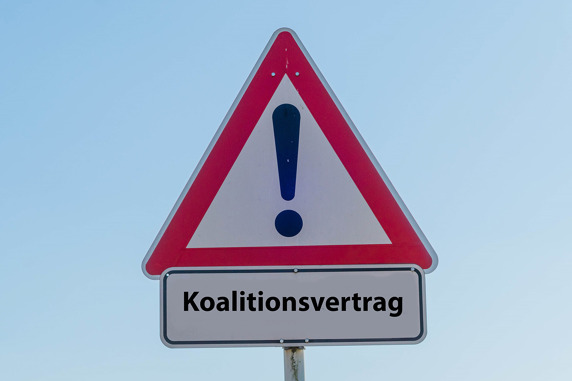 Straßenschild mit einem Ausrufezeichen und dem Text "Koalitionsvertrag" darauf