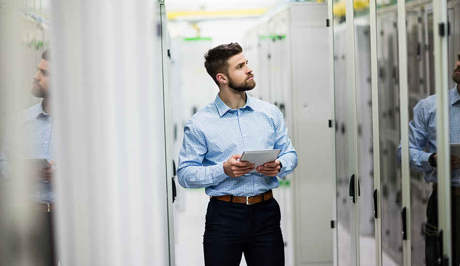 Mann in einem Rechenzentrum mit Tablet in der Hand