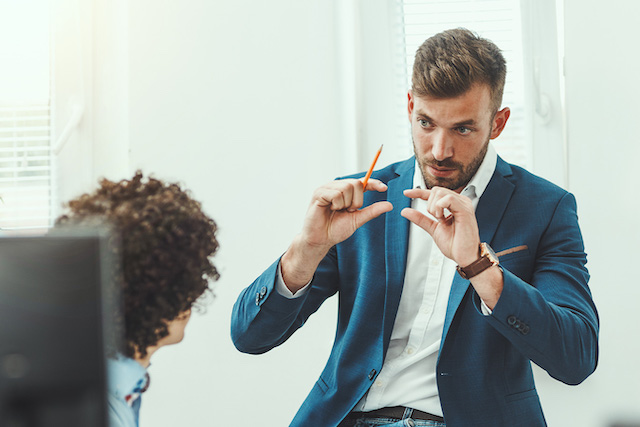 Mann, der einer Frau gestikulierend etwas erklärt. Links im Vordergrund ein Bildschirm