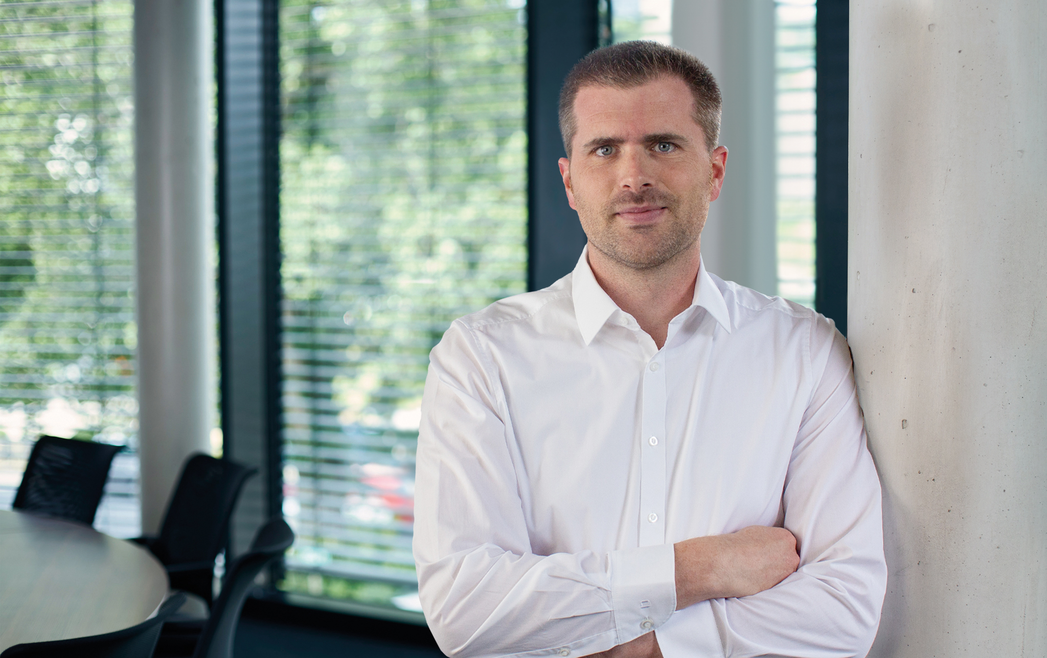 Björn Wäschenbach in weißem hemd, stehend und lachend